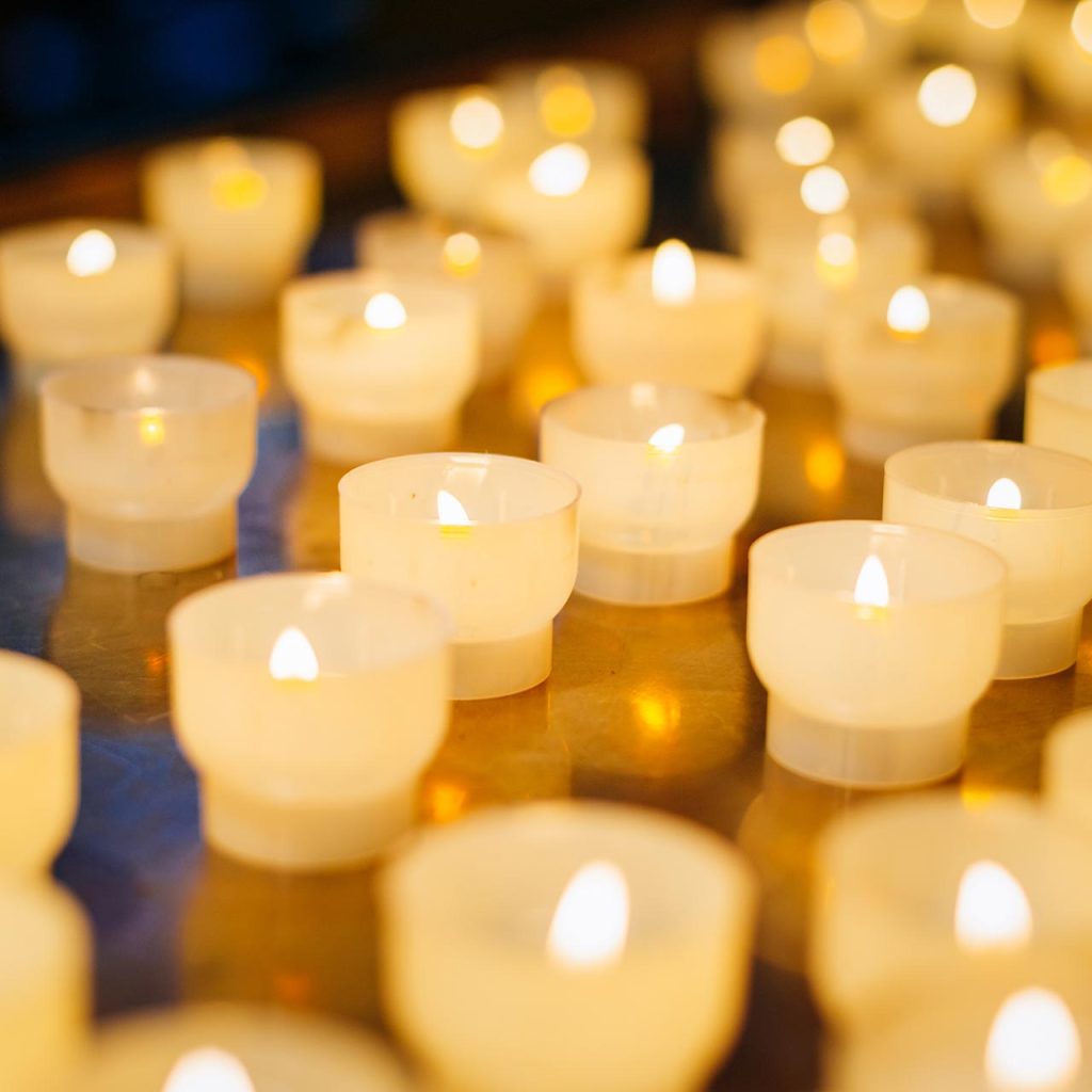Multiple lighted votive candles with an orange glow