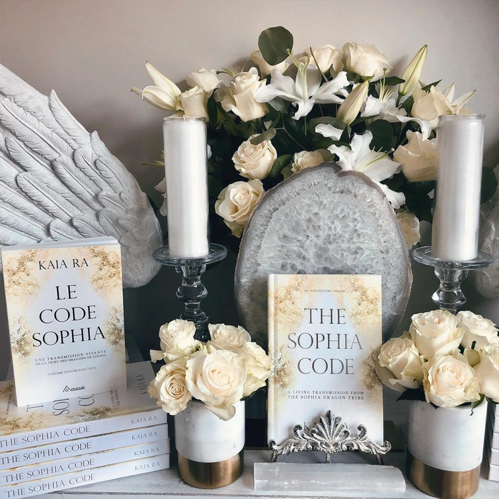 Copies of The Sophia Code book surrounded by candles and flowers